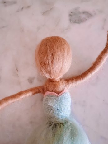 A doll with a dress being made